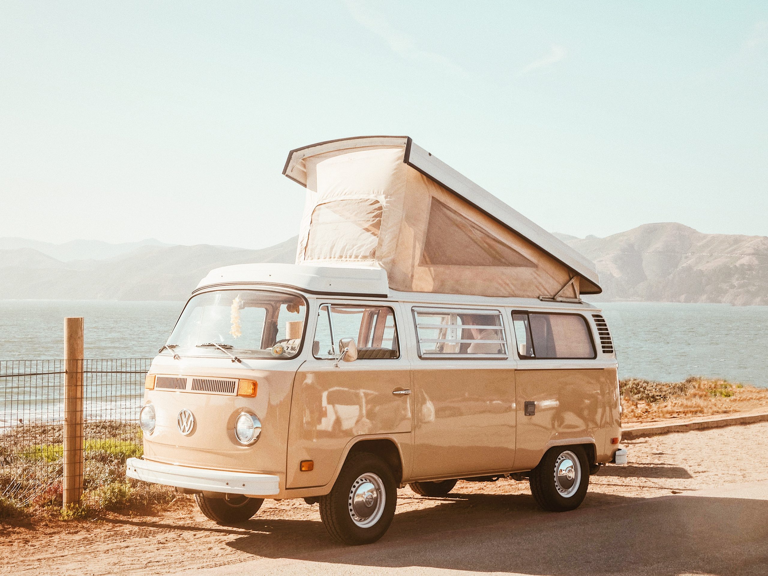 VW camper van parked on side of road with high roof opened