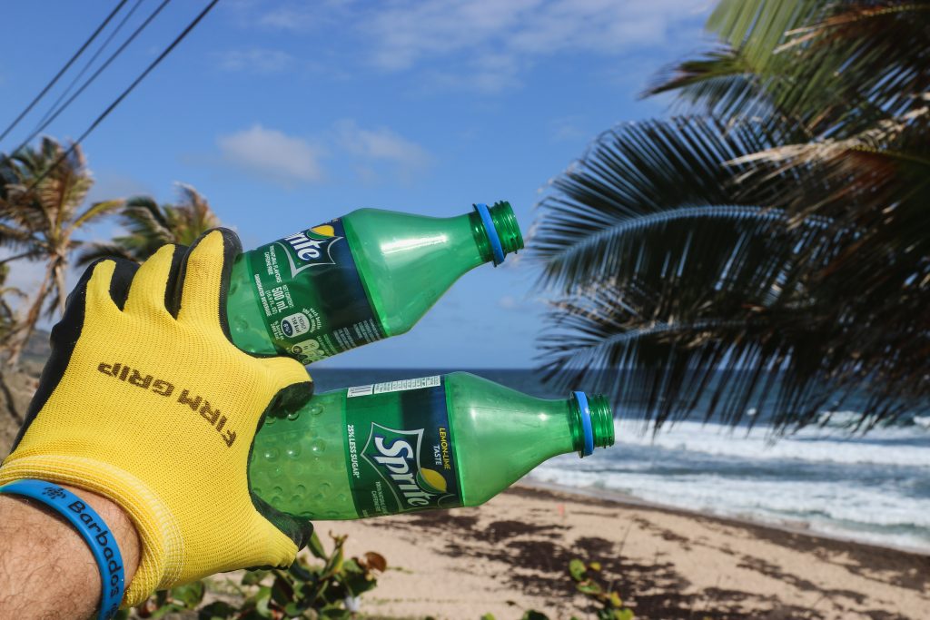 Don't Litter, green plastic bottles on the beach being collected