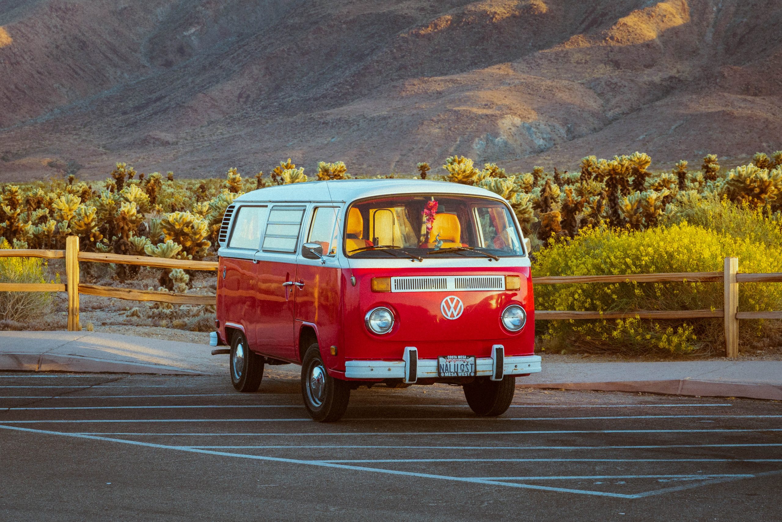 Red and white camper van parked in front of mountains