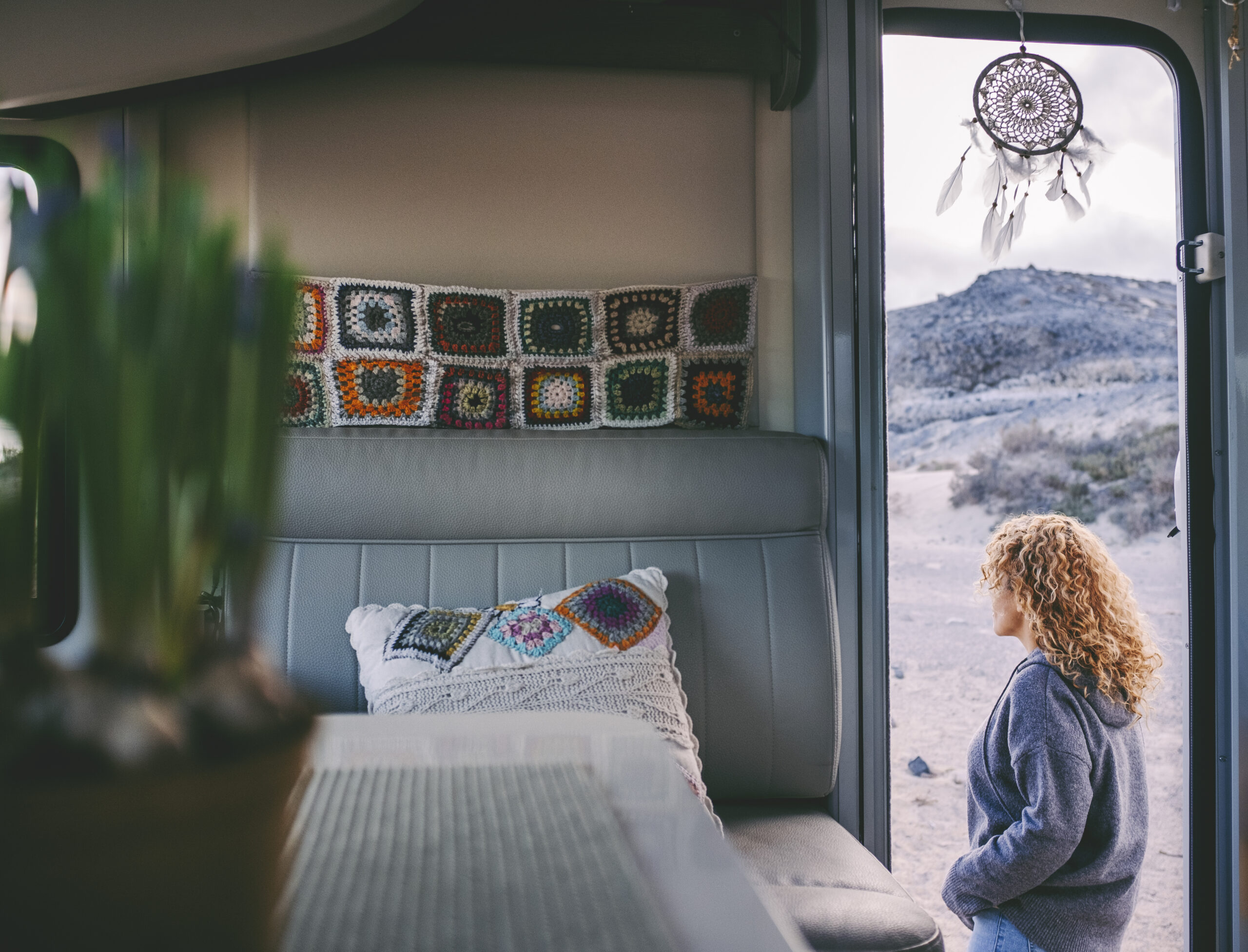 Woman walking outside her camper van. View from interior. Knit d
