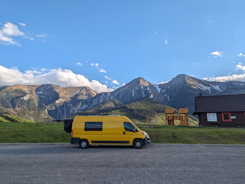 Yellow Peugeot boxer van parked up with green rolling hills in the background