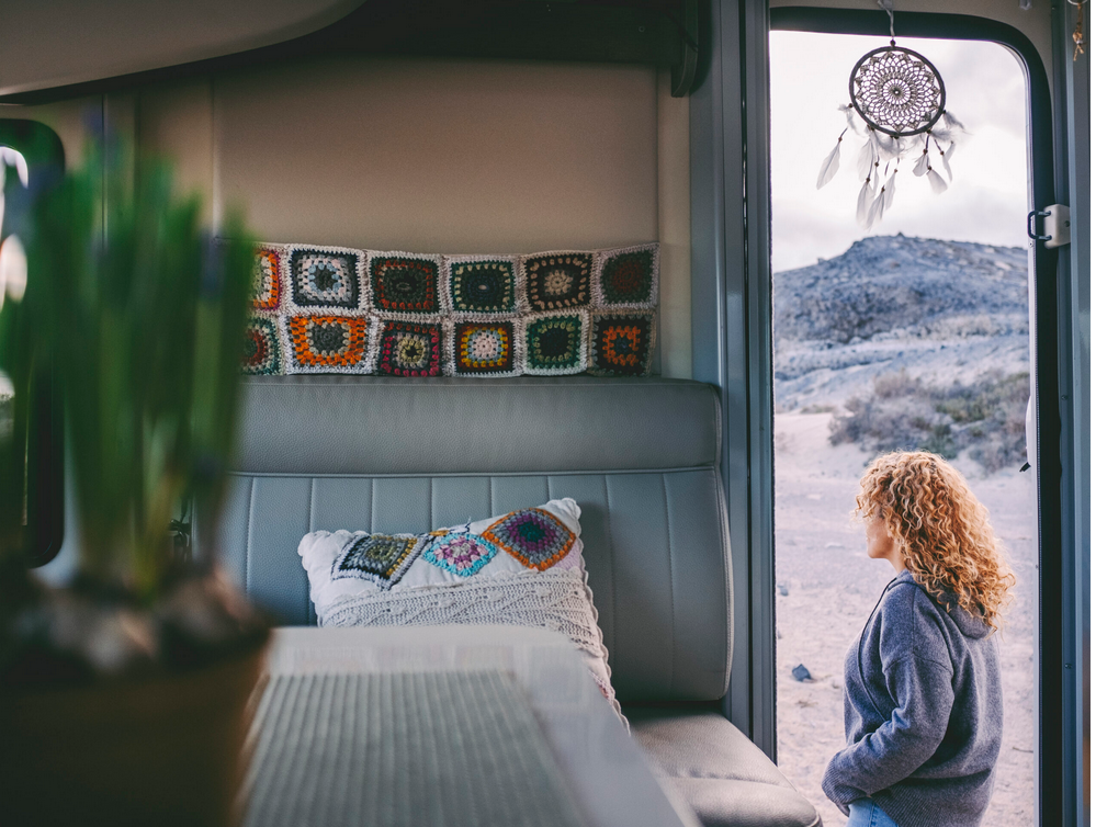 Converted camper van with personalized inside decor with van door open showing woman outside